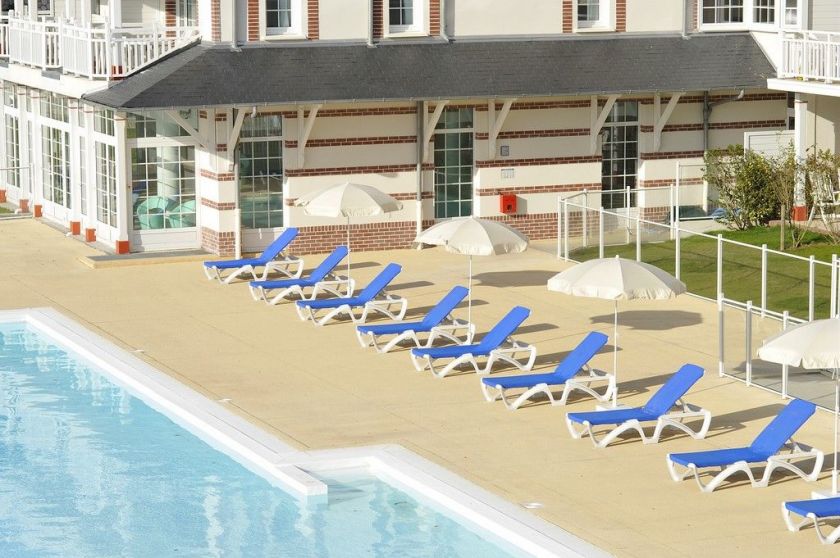 La piscine extérieure et son solarium pour un bain de soleil en famille