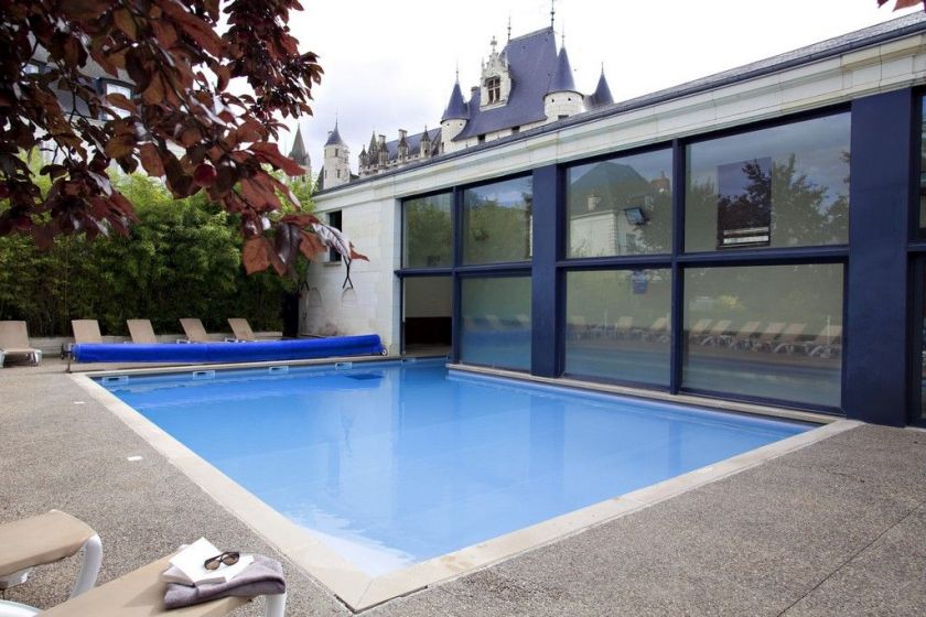 La piscine semi-couverte de 100m² et sa terrasse avec transats et parasols